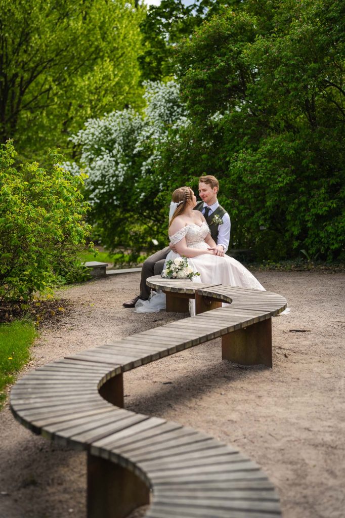 Brudparet sitter på en svingbar bänk og koser seg i Botanisk hage i Oslo.