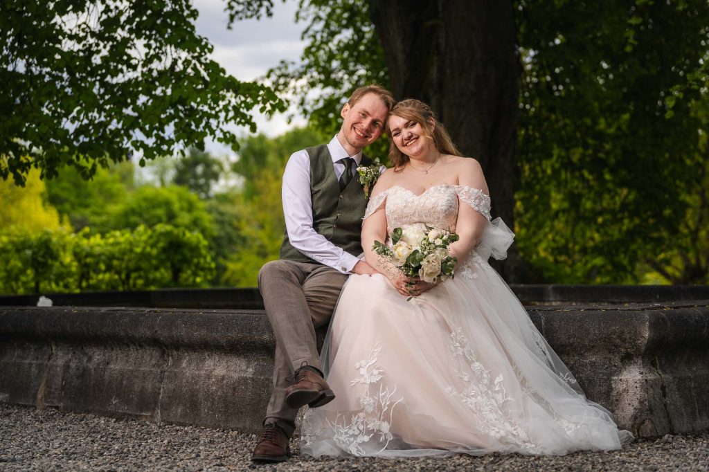 Brudeparet sitter sammen ved fontenen i Botanisk hage i Oslo.