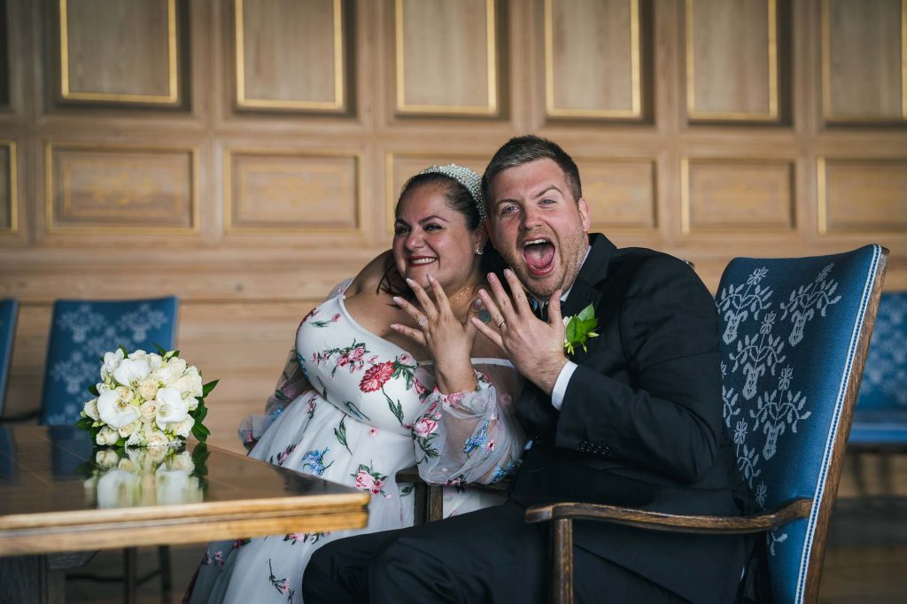 Nygifte viser frem ringene sine og smiler.