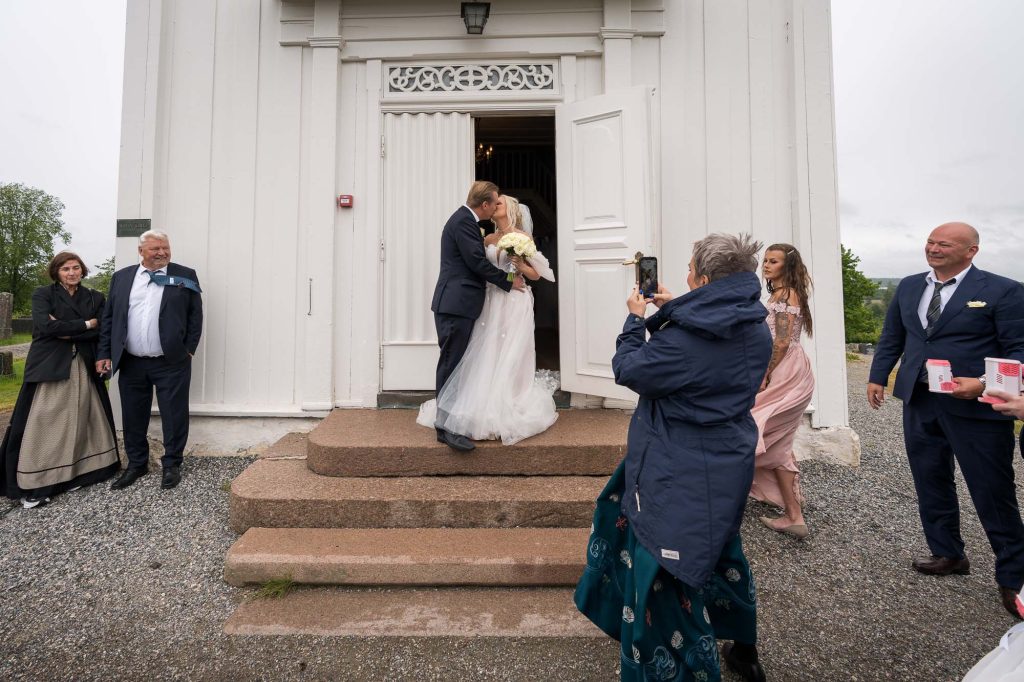 De nygifte kysser hverandre på trappen utenfor Hovin kirke.
