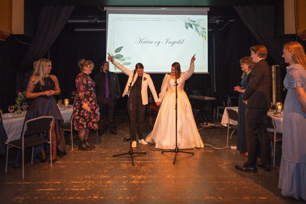 Brudeparet er på scenen og ønsker sine bryllupsgjester velkommen til bryllupsfesten i Sagene festivitetshus.