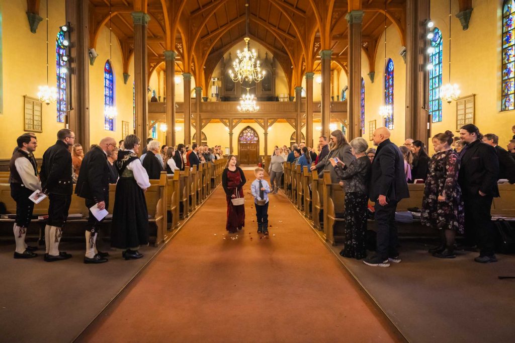 Blomsterpike och blomstergutt strør blomsterblader i midtgangen før brudeparet kommer inn til vielsen i Kampen kirke.