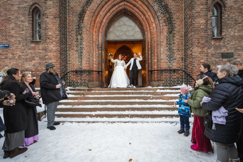 Samkjønnet vinterbryllup i Kampen kirke. De nygifte på trappen utenfor kirken.