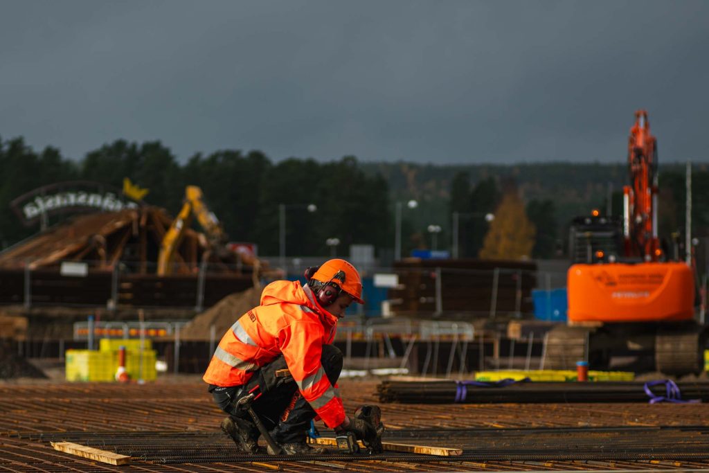 Byggarbeider på en byggeplass iført en oransje regnjakke